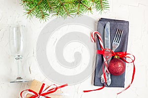 Christmas table place setting with tree fir branches, napkin, fork, knife, ball, candy canes, gift and glass. Christmas holidays