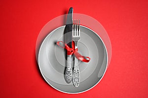 Christmas table with a plate, fork, knife. top view, copy space. against a red background
