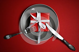 Christmas table with a plate, fork, knife. top view, copy space. against a red background