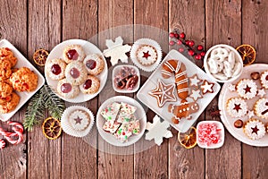 Christmas baking table scene of mixed sweets and cookies, above view over rustic wood