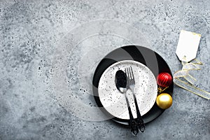 Christmas table set minimalism style in black and red on a plain gray background with black cutlery. Top view.,