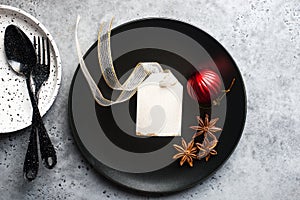 Christmas table set minimalism style in black and red on a plain gray background with black cutlery. Top view.,