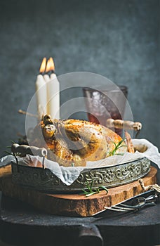 Christmas table set with roasted whole chicken, candles and wine