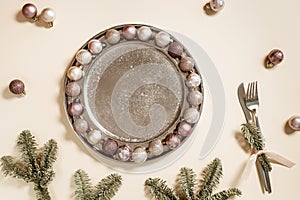 Christmas table setting concept, shining small Christmas balls beige pink color in metal plate, knife, fork decorated