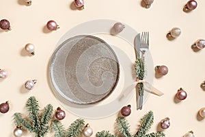 Christmas table setting concept, shining small Christmas balls beige pink color in metal plate, knife, fork decorated