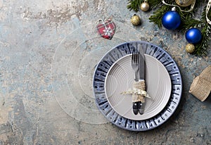 Christmas table setting on decor background. Blue and gray plate, cutlery, festive decorations