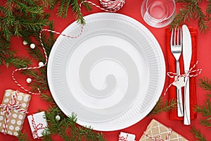 Christmas table setting with empty plate, cutlery and gift boxes