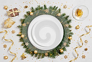 Christmas table setting with empty white plate and gold decorations on gray table. Copy space, top view, flat lay