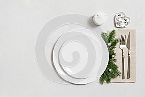 Christmas table setting with empty white plate and silver decorations. New Year serving on white background. Festive dinner. Copy