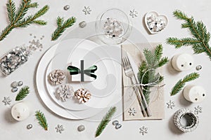 Christmas table setting with festive silver decorations, fir branches and cones on white background. Preparing for Christmas