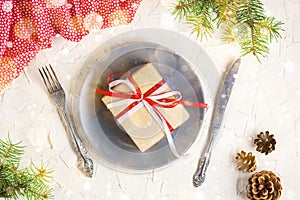 Christmas table setting with gift on plate on white table. Xmas concept top view