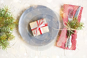 Christmas table setting with gift on plate on white table. Xmas concept top view