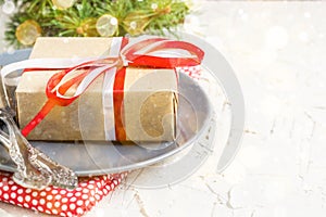 Christmas table setting with gift on plate on white table. Xmas concept top view