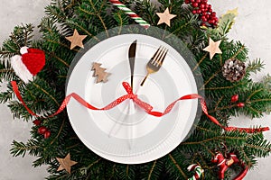 Christmas table setting with gold cutlery and on white plate on natural fir branch background