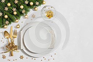 Christmas table setting with golden festive decorations and empty plate on gray background. Happy new year. Space for text. Winter