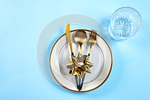 Christmas table setting with modern dishware and decorations on blue background. Top view. New Year place setting