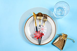 Christmas table setting with modern dishware and decorations on blue background. Top view. New Year place setting