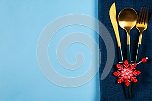 Christmas table setting with modern dishware and decorations on blue background. Top view. New Year place setting