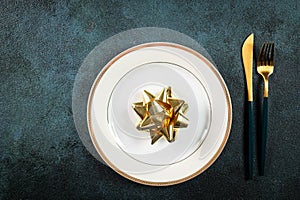 Christmas table setting with modern dishware and decorations on dark background. Top view. New Year place setting