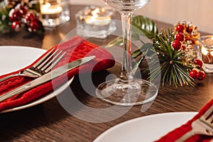 Christmas table setting. Plate and cutlery on red napkin. Candles burning on table on Christmas Eve. Preparing for