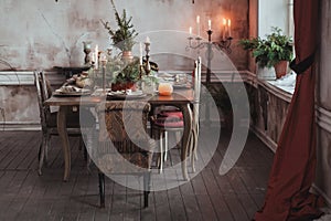 Christmas table setting. Vintage chairs, natural pine tree branches, candles. Rural or rustic style decorations