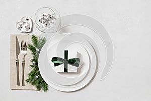 Christmas table setting on white background with copy space. New Year gift in a plate. Christmas serving with festive decor. Top