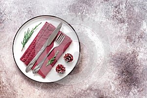 Christmas table setting. White plate, cutlery and napkin on rustic background. Top view, flat lay, copy space