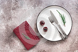 Christmas table setting. White plate, cutlery and napkin on rustic background. Top view, flat lay, copy space