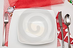 Christmas table setting with white plates and red decorations