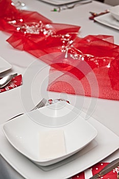 Christmas table setting with white plates and red decorations