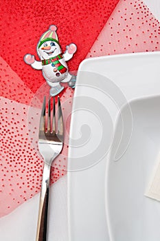 Christmas table setting with white plates and red decorations