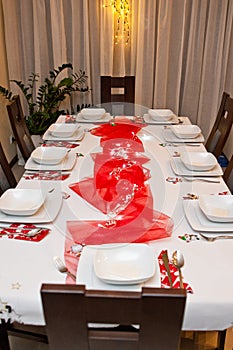 Christmas table setting with white plates and red decorations