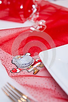 Christmas table setting with white plates and red decorations