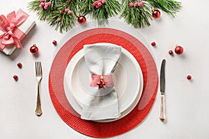 Christmas table setting with white and red holiday decorations on white table. Top view
