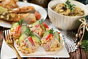 Christmas table with vegetable salad served in shortcrust pastry tartlets, fried carp and sauerkraut