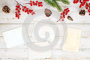 Christmas theme background with blank photo paper and decorating elements on white wood table.
