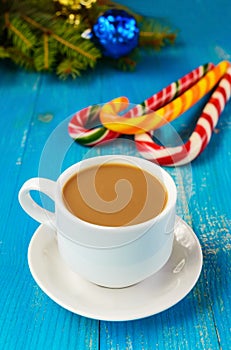 Christmas theme. A cup of coffee with milk cappuccino, in the form of bright candy canes and green spruce branches