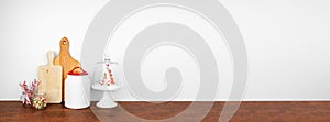 Christmas theme kitchenware, candy and decor on a wooden shelf. Banner against a white wall background.