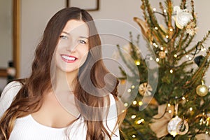 Christmas time and holiday mood concept. Happy smiling woman and decorated xmas tree lights on background