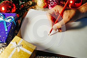 christmas time human hand writing unrecognizable with red pencil on white paper