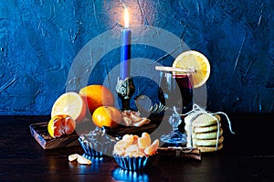 Christmas time, winter, mulled wine in glass, cinnamon, orange and mandarin, cookies and chocolate, a candle in a