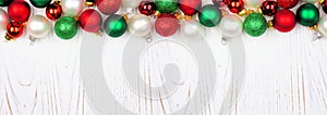 Christmas top border of red, white and green ornaments on a white wood banner background