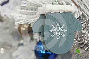 Christmas toy blue wooden glove in rustic style on Christmas tree. S ingle New Year toy on white spruce branch close up