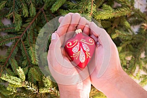 Christmas toy in form of red heart in hands