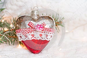 Christmas toy heart on a white knitted warm sweater surrounded by garlands.