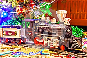 Christmas toy railroad near a Christmas tree with lights