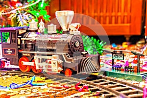 Christmas toy railroad near a Christmas tree with lights