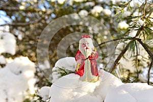 Christmas toy Santa Claus on branch with pine tree needles in the snow. Christmas balls decoration. oncept of preparing for the