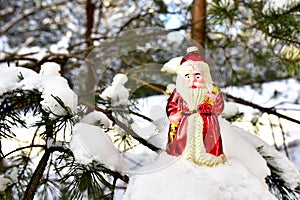 Christmas toy Santa Claus on branch with pine tree needles in the snow. Christmas balls decoration. oncept of preparing for the