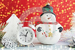 Christmas toy snowman, alarm clock, silver snowflake and tinsel on a red background.